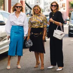 Trzy kobiety prezentują stylowe propozycje, jak się ubrać na Wielkanoc: biała koszula i niebieska spódnica, wzorzysta bluzka i czarna spódnica, czarny total look.