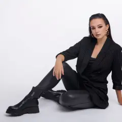 Elegancka kobieta w czarnym garniturze i spodniach woskowanych, prezentująca stylowe, nowoczesne stylizacje.