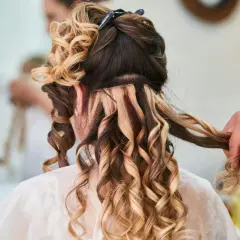 Fryzury na wesele loki włosy średnie. Stylista tworzy loki na średniej długości włosach, dodając objętości i blasku.