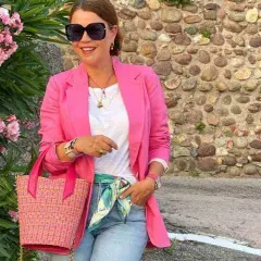 Kobieta w różowej marynarce i jeansach, z torebką i apaszką, tworzy idealny outfit na randkę.