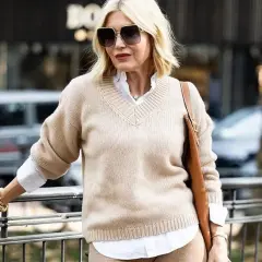 Eleganckie kobiece stylizacje: beżowy sweter, biała koszula, brązowa torebka i złota biżuteria.