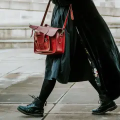 Czarne martensy i czerwona torba tworzą stylowy zestaw. Długa, czarna sukienka dodaje elegancji.