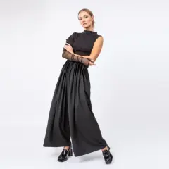 Elegancki strój do teatru na komedię: czarny top z siateczkowymi rękawami i szerokie, marszczone spodnie.