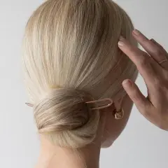 Elegancki kok z wsuwką to jedna z modnych fryzur na wesele. Delikatna biżuteria podkreśla styl.
