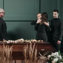 Smutek i żałoba. Rodzina w czerni przy trumnie. Jak się ubrać na pogrzeb? Elegancko i z szacunkiem.
