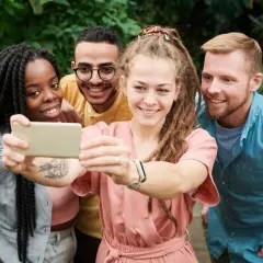 Uśmiechnięci przyjaciele robią selfie w otoczeniu zieleni. Pokazują, że cechy dobrego przyjaciela to wspólne chwile i radość.