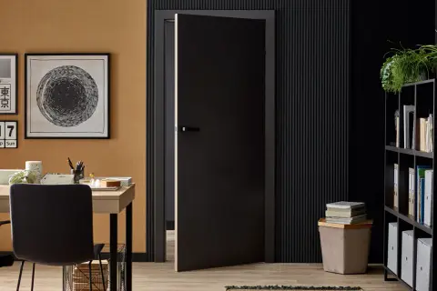 Ciepły, miodowy kolor ściany i czarne akcenty tworzą stylowe wnętrze. Jaki kolor pasuje do czarnego? Złoto, beż i zieleń roślin dodają elegancji.