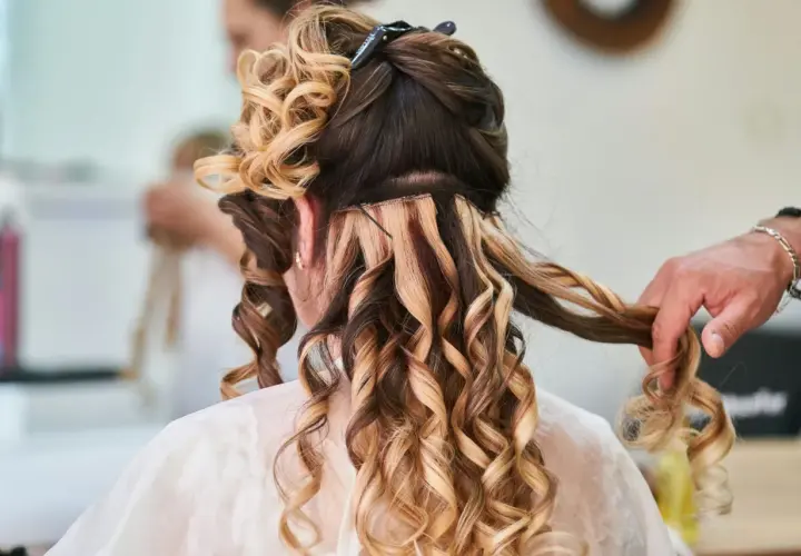Fryzury na wesele loki włosy średnie. Stylista tworzy loki na średniej długości włosach, dodając objętości i blasku.