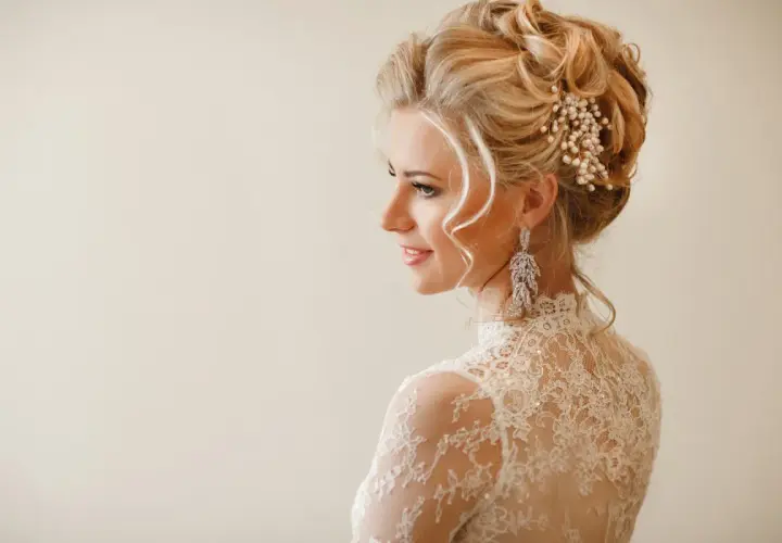 Eleganckie fryzury na wesele średnie włosy upięcia. Delikatne loki i perłowa ozdoba we włosach panny młodej.