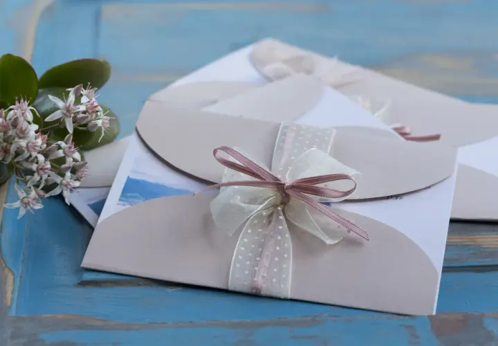 Eleganckie zaproszenia ślubne z kokardkami. Jak odmówić przyjścia na wesele? Delikatne kwiaty dodają uroku.