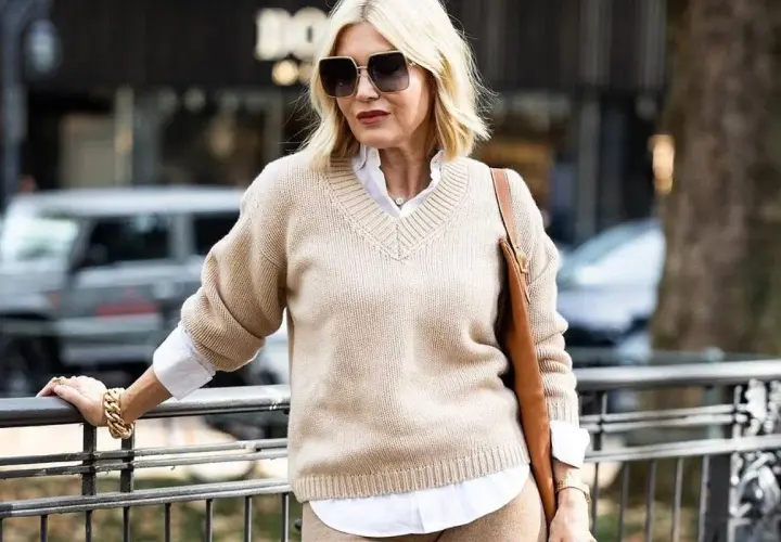 Eleganckie kobiece stylizacje: beżowy sweter, biała koszula, brązowa torebka i złota biżuteria.