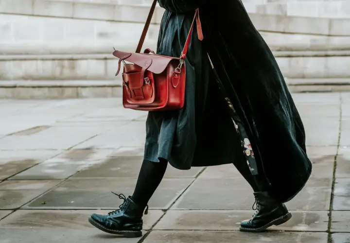 Czarne martensy i czerwona torba tworzą stylowy zestaw. Długa, czarna sukienka dodaje elegancji.