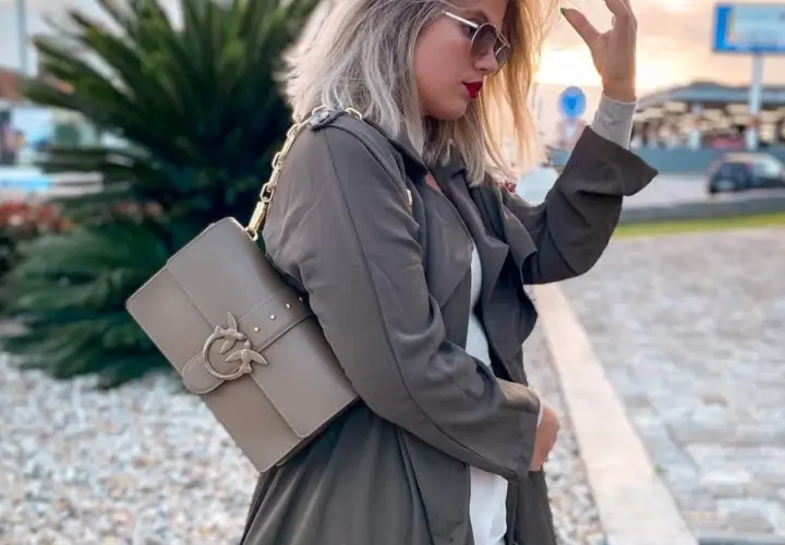 Elegancka torebka Pinko idealnie dopełnia stylowe torebka pinko stylizacje. Kobieta w płaszczu i okularach przeciwsłonecznych prezentuje modny dodatek.