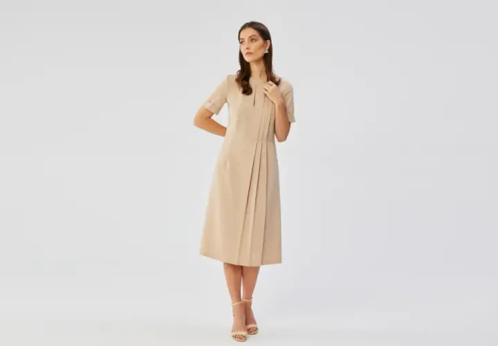 Elegancka beżowa sukienka z subtelnymi plisami, idealna na stylizacje na wesele.