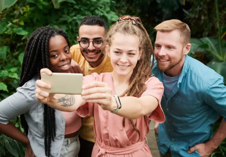 Uśmiechnięci przyjaciele robią selfie w otoczeniu zieleni. Pokazują, że cechy dobrego przyjaciela to wspólne chwile i radość.