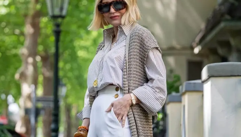 Elegancka kobieta w białych spodniach i pasiastym swetrze prezentuje stylowe wiosenne stylizacje.