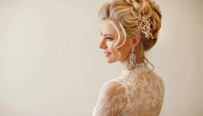 Eleganckie fryzury na wesele średnie włosy upięcia. Delikatne loki i perłowa ozdoba we włosach panny młodej.