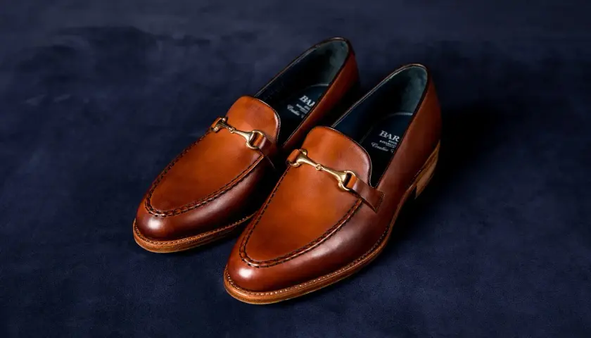 Eleganckie, brązowe loafersy do sukienki z ozdobnym złotym elementem, idealne na specjalne okazje.