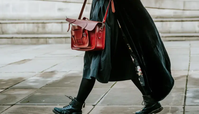 Czarne martensy i czerwona torba tworzą stylowy zestaw. Długa, czarna sukienka dodaje elegancji.