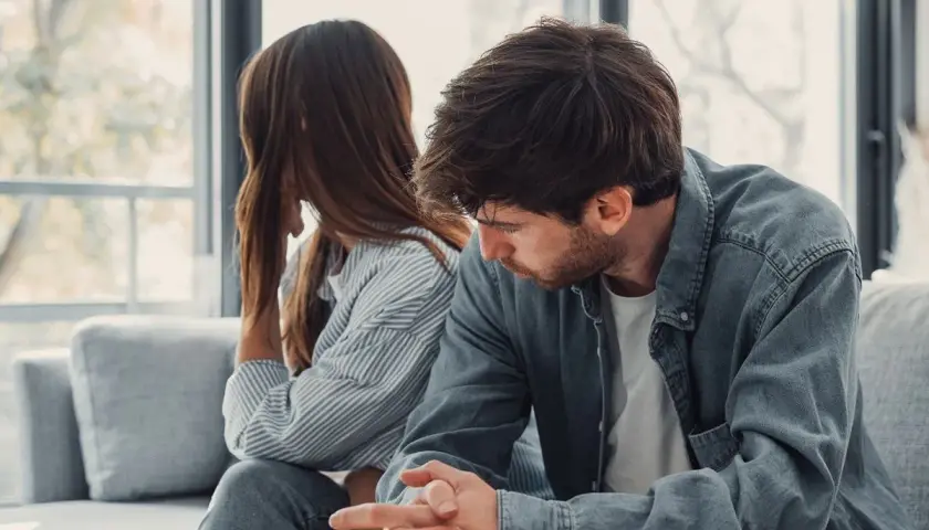Para siedzi na kanapie, odwrócona od siebie. Jej niska inteligencja emocjonalna utrudnia porozumienie.