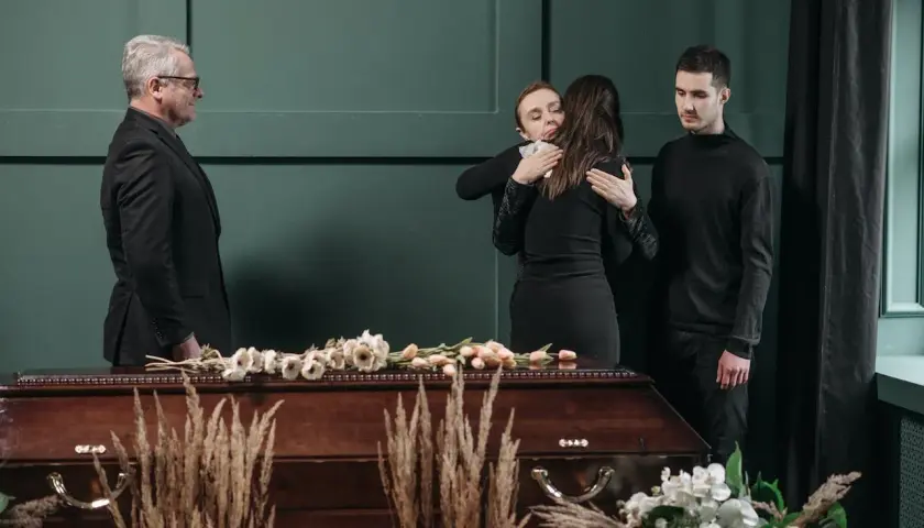 Smutek i żałoba. Rodzina w czerni przy trumnie. Jak się ubrać na pogrzeb? Elegancko i z szacunkiem.