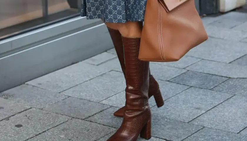 Eleganckie kozaki za kolano w brązowym kolorze, z fakturą skóry krokodyla, idealne na imprezę. Stylizacja uzupełniona o torebkę w tym samym odcieniu.