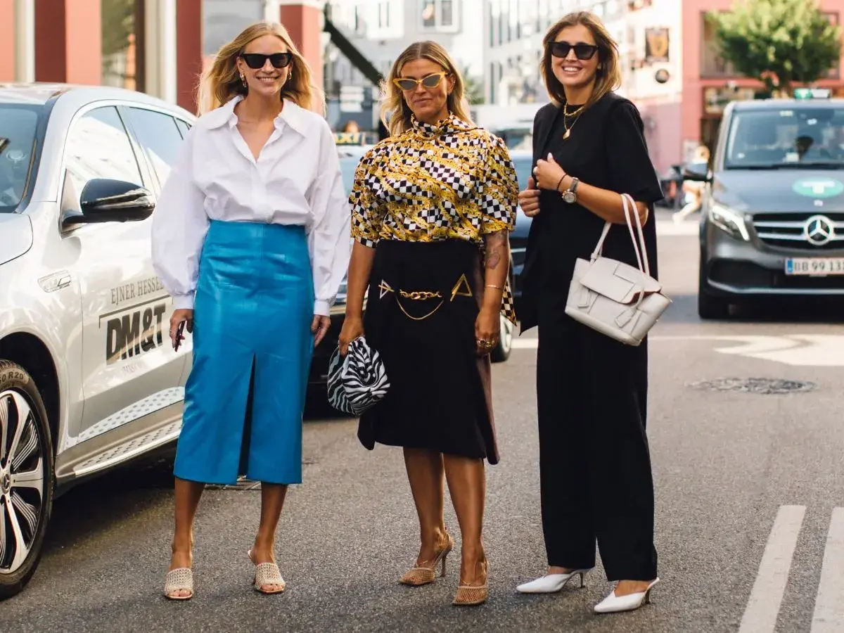 Trzy kobiety prezentują stylowe propozycje, jak się ubrać na Wielkanoc: biała koszula i niebieska spódnica, wzorzysta bluzka i czarna spódnica, czarny total look.