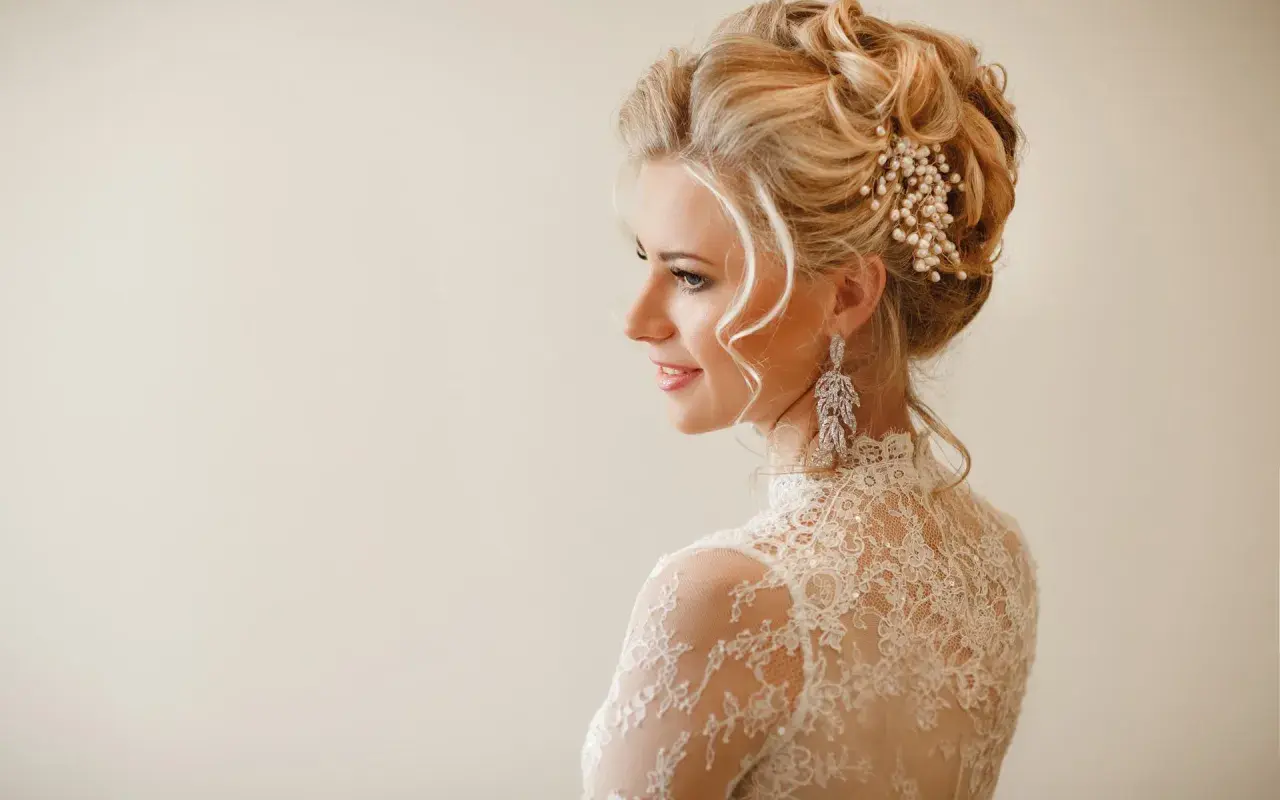 Eleganckie fryzury na wesele średnie włosy upięcia. Delikatne loki i perłowa ozdoba we włosach panny młodej.