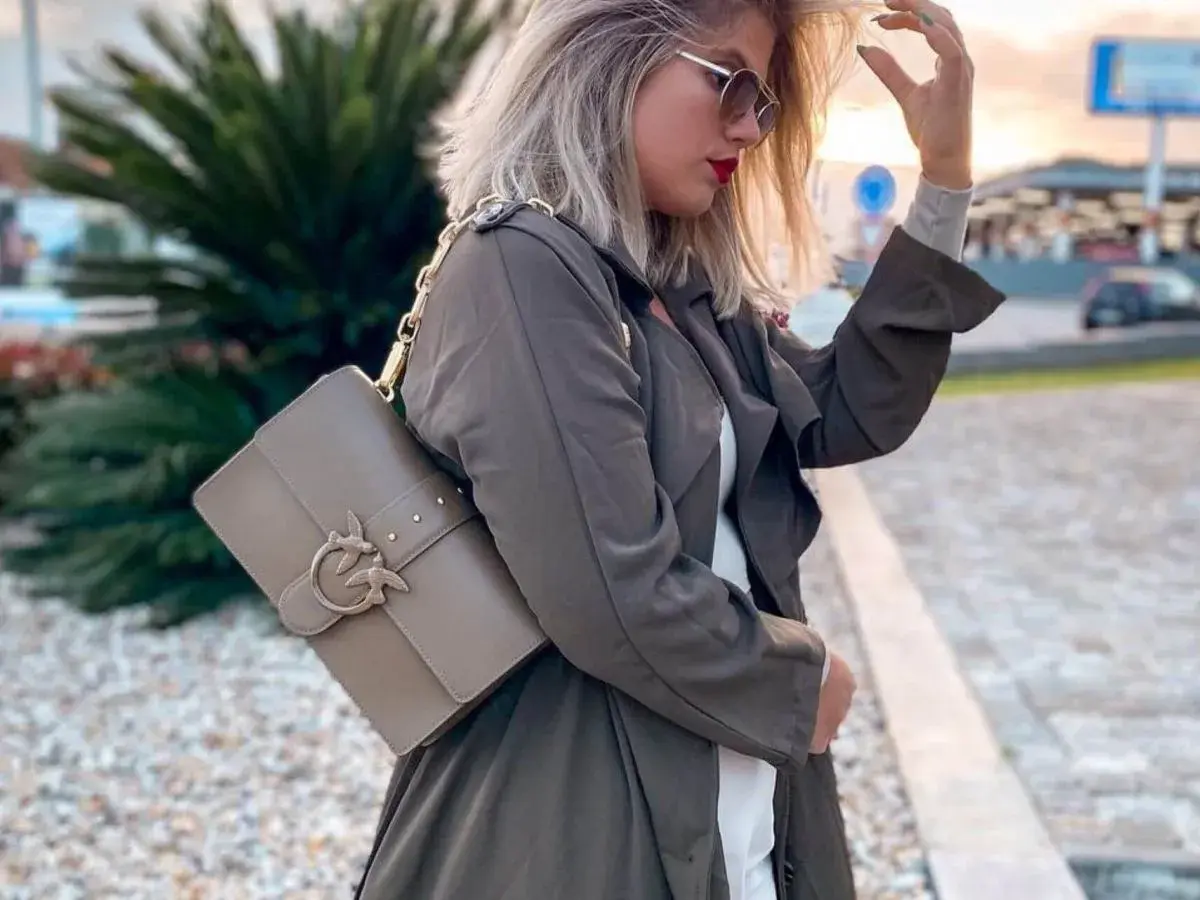 Elegancka torebka Pinko idealnie dopełnia stylowe torebka pinko stylizacje. Kobieta w płaszczu i okularach przeciwsłonecznych prezentuje modny dodatek.