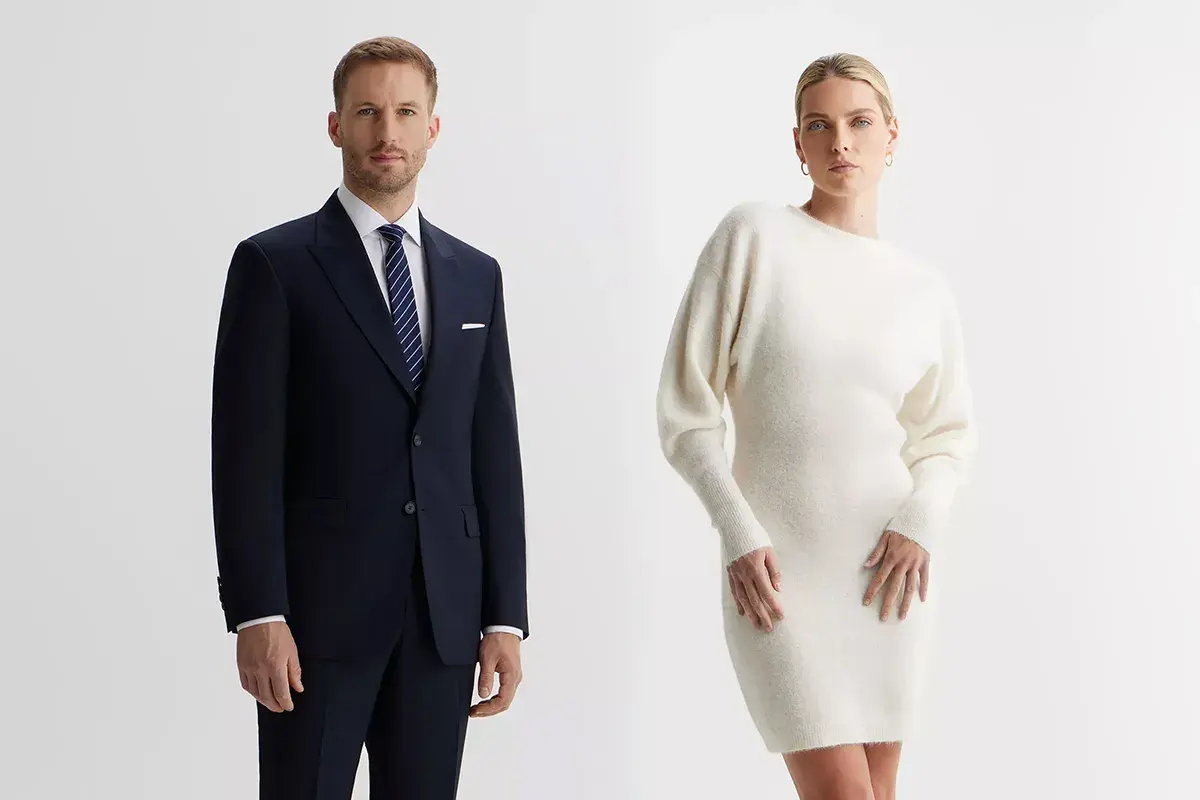 Elegancki mężczyzna w granatowym garniturze i kobieta w kremowej sukience. Idealne stylizacje, jak się ubrać na wigilię firmową.