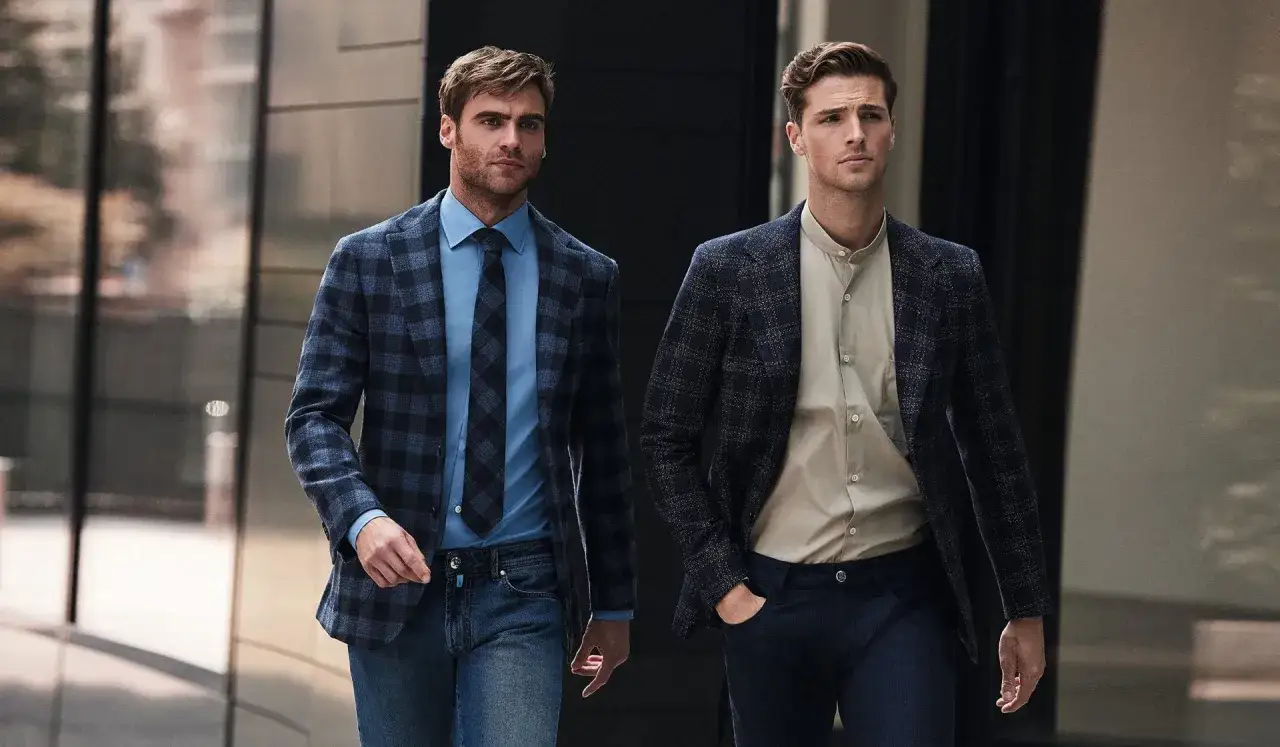 Dwóch mężczyzn w eleganckich, ale swobodnych strojach typu business casual idzie ulicą.
