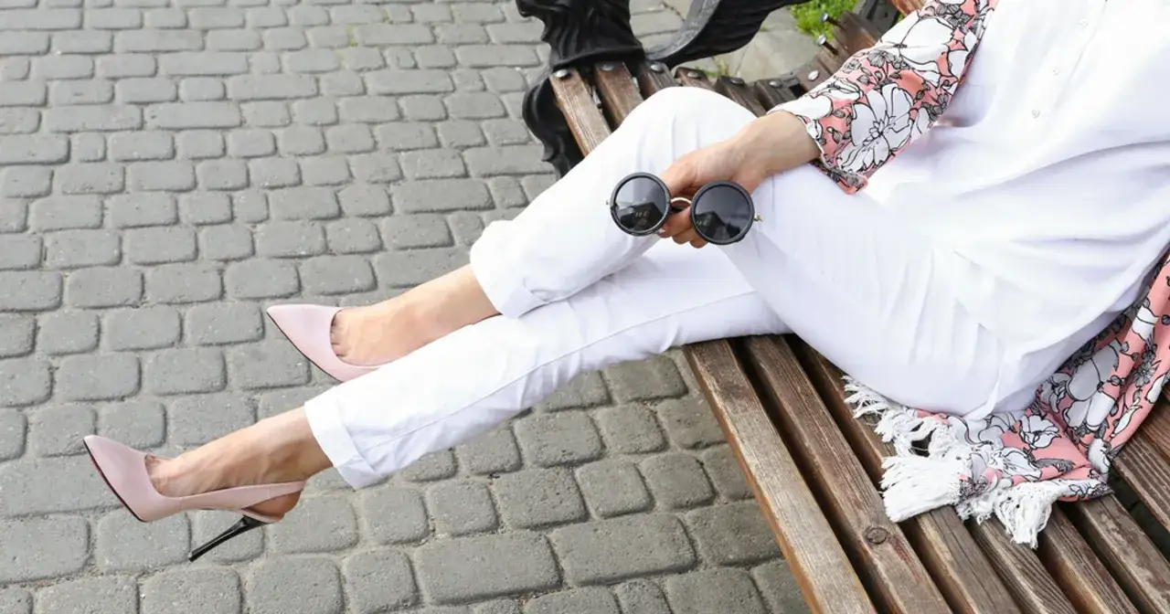 Elegancka stylizacja: białe spodnie, pudrowy r&oacute;ż szpilki i kwiecisty narzutka. Idealna inspiracja, co ubrać do białych spodni na letnie dni.