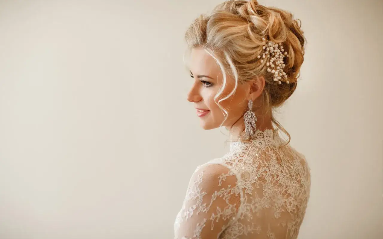 Romantyczna fryzura na wesele z perłowym zdobieniem i elegancką suknią z koronki.