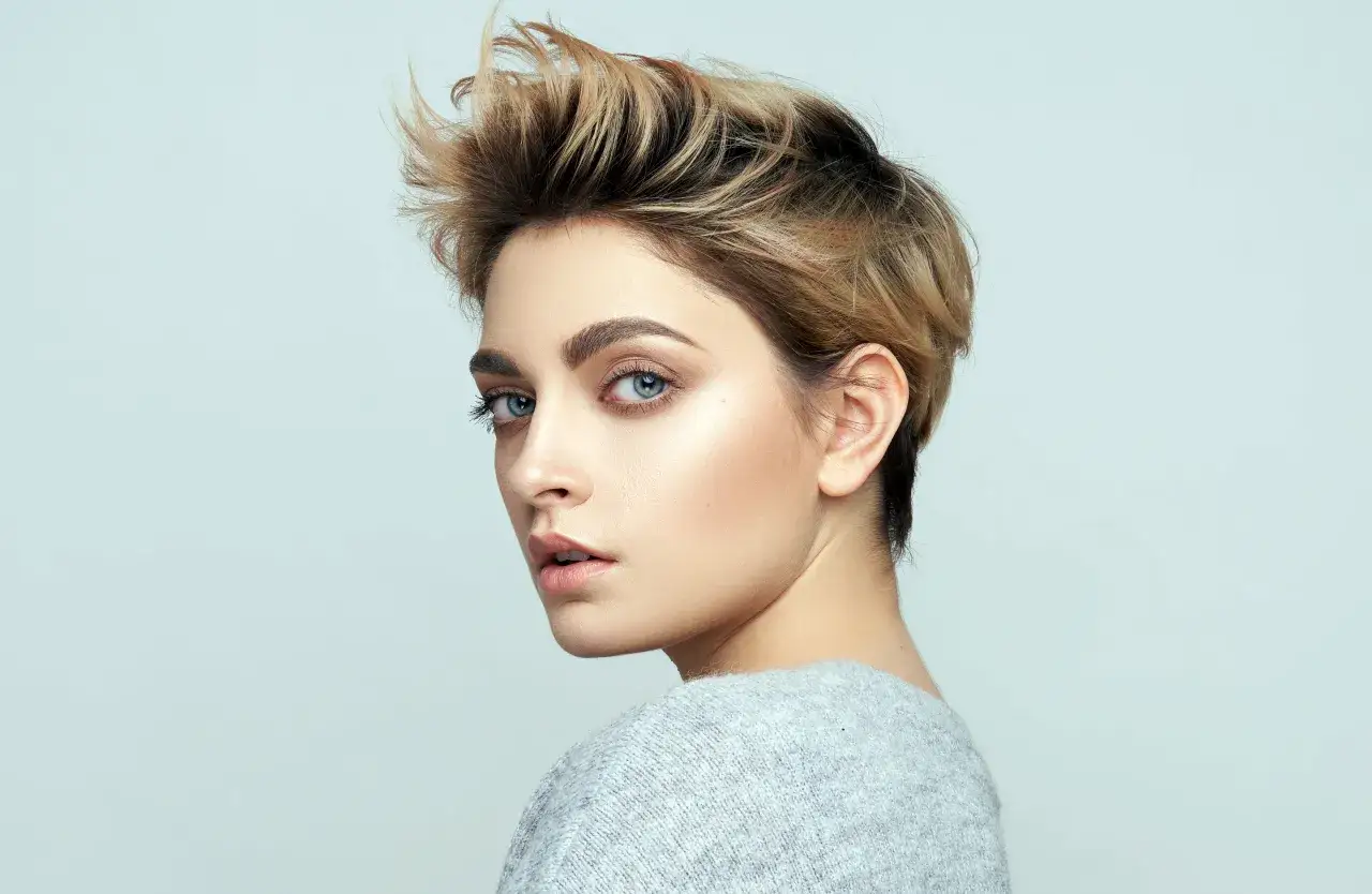 Kobieta z burzą blond włosów, prezentująca modną fryzurę. Jej spojrzenie przyciąga uwagę.