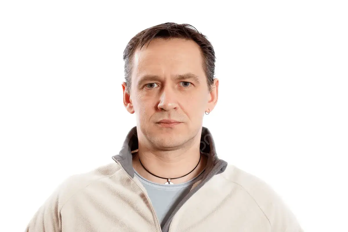 Portret dojrzałego mężczyzny w beżowej bluzie. Jego spojrzenie sugeruje głębię przemyśleń, jakby dzielił się mądrością życiową, niczym w swoich cytatach.