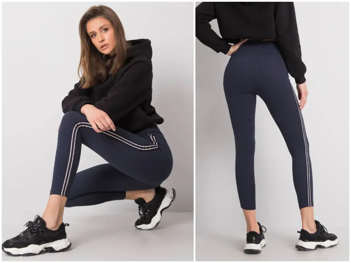Modelka prezentuje granatowe legginsy z lampasami i podpowiada, jakie buty do legginsów pasują najlepiej – sportowe sneakersy.