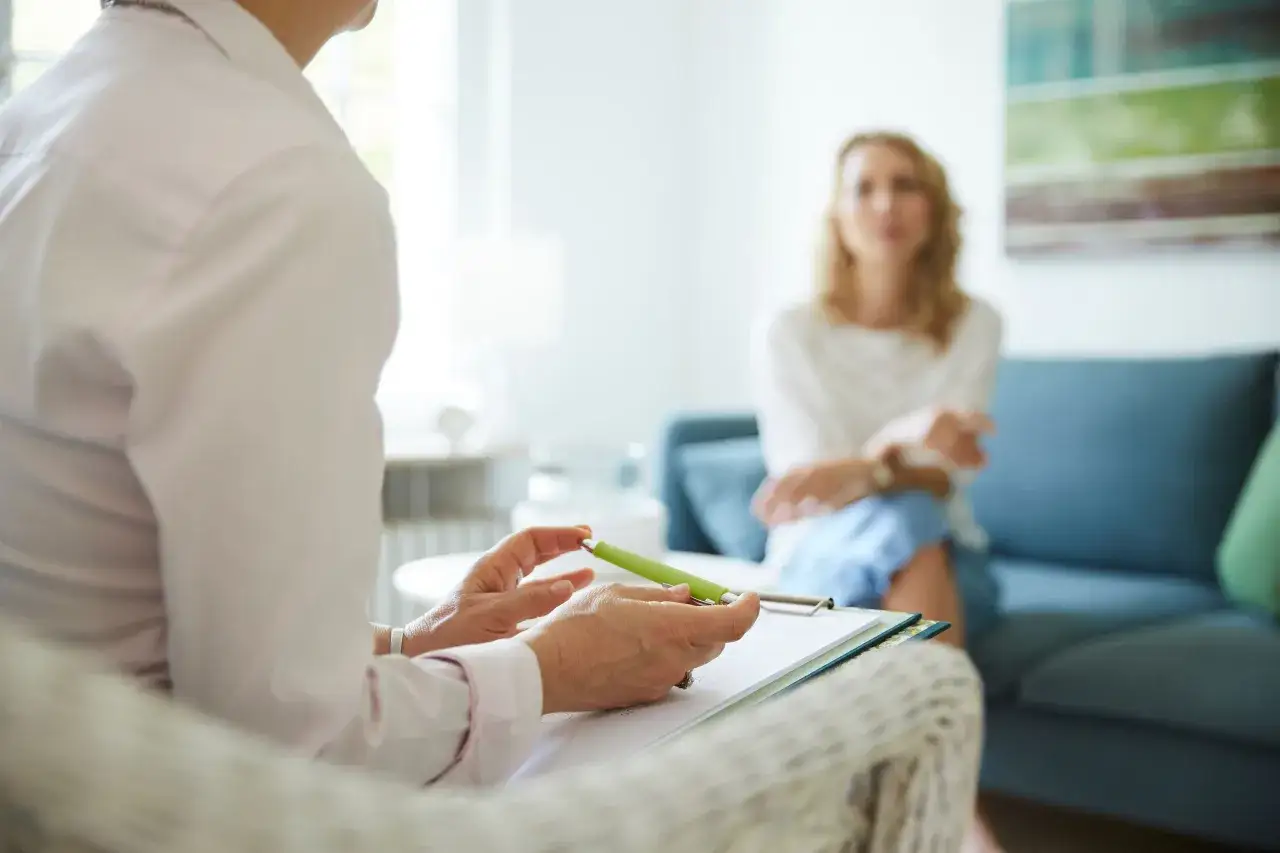Terapeuta prowadzi dialog motywujący z pacjentką, notując ważne spostrzeżenia.